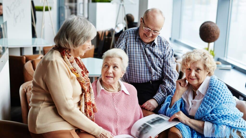 A group of three elderly women sitting on a couch with a man